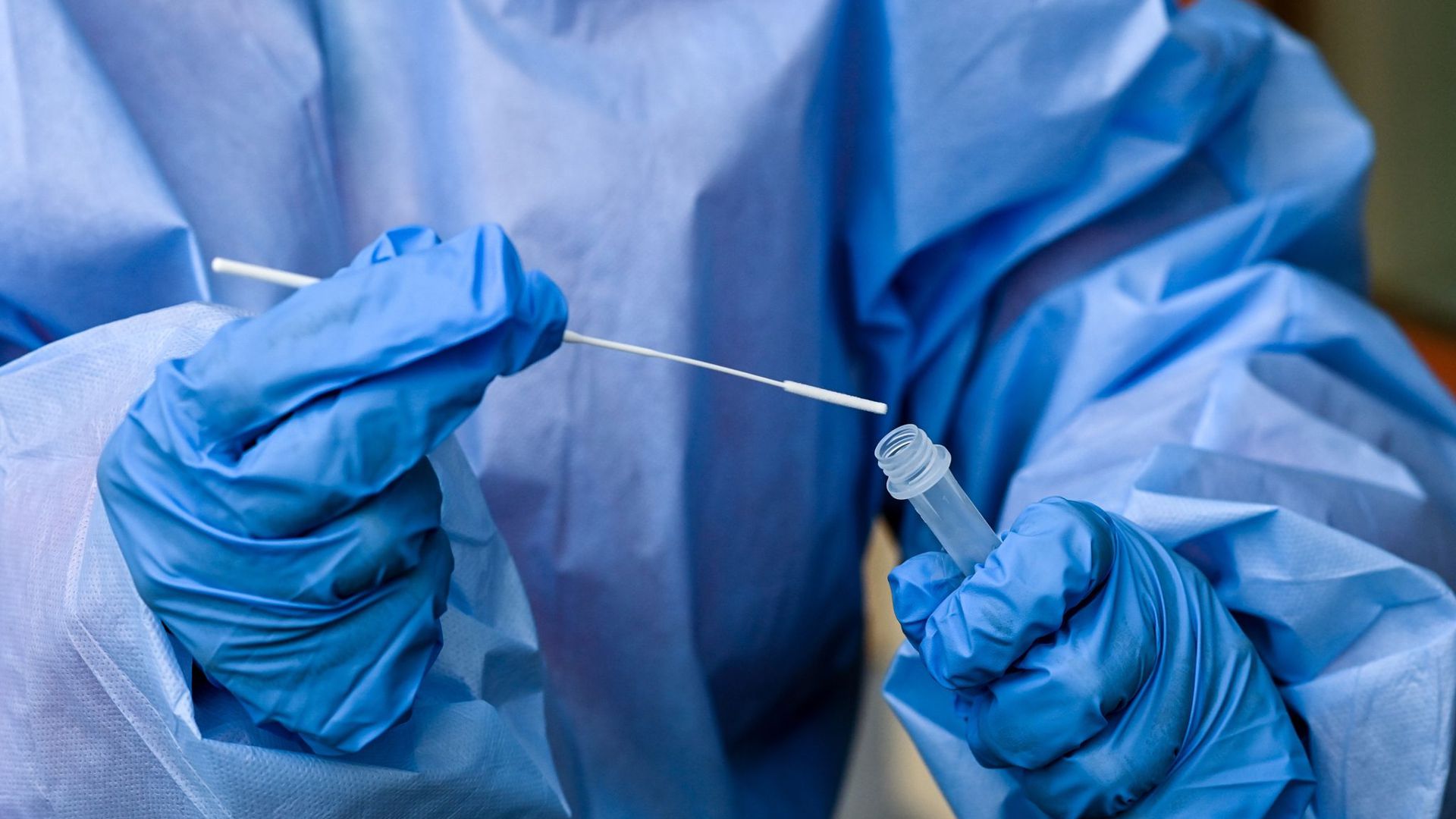 Eine Krankenschwester legt ein Abstrichstäbchen in ein Teströhrchen mit der Flüssigkeit eines Corona-Schnelltests.