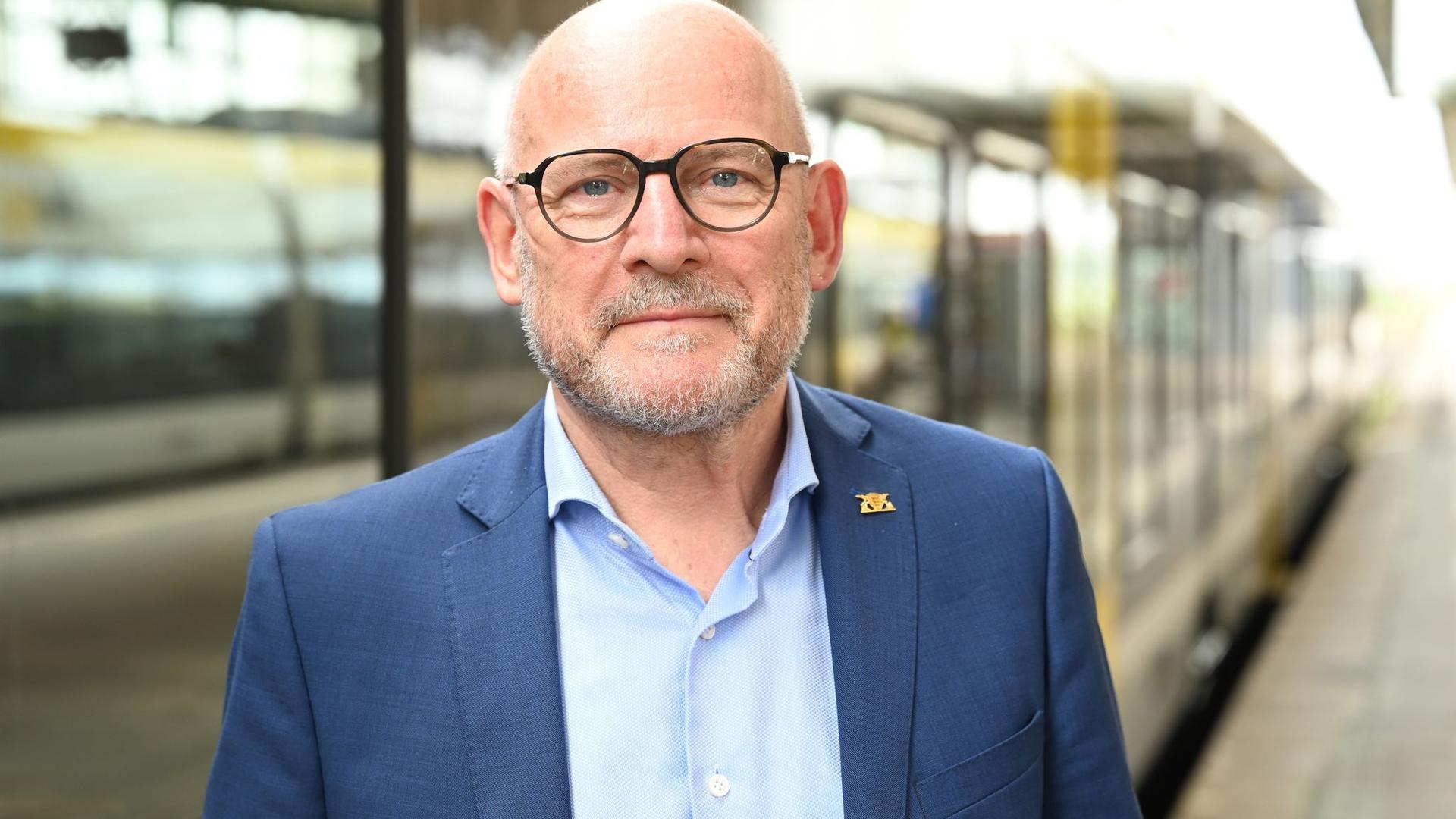 Baden-Württembergs Verkehrsminister Winfried Hermann steht vor einem Regionalzug.
