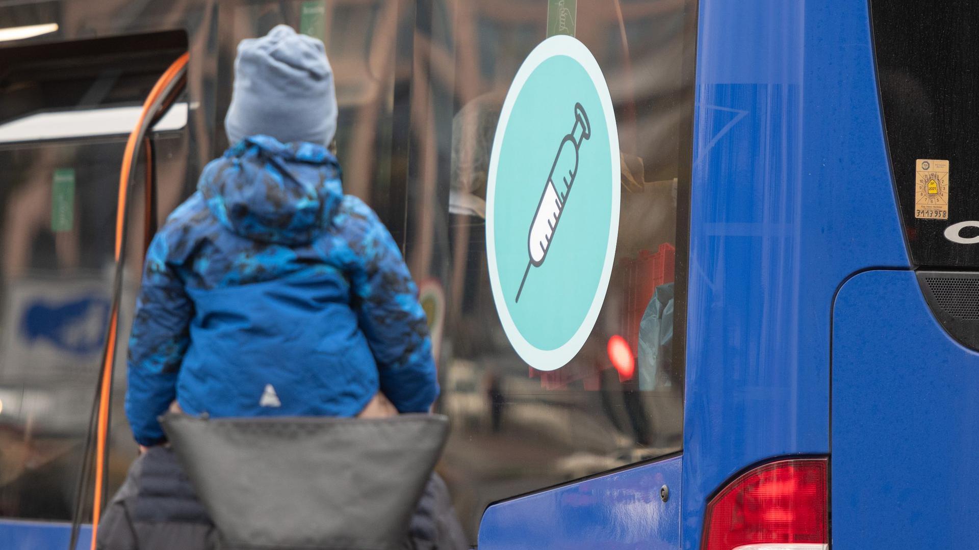 Ein Mann mit einem Kind auf den Schultern geht an einem mobilen Impfzentrum vorbei.