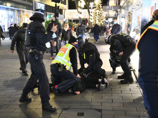 Polizisten in Schutzausrüstung ringen einen Protestierer zu Boden.