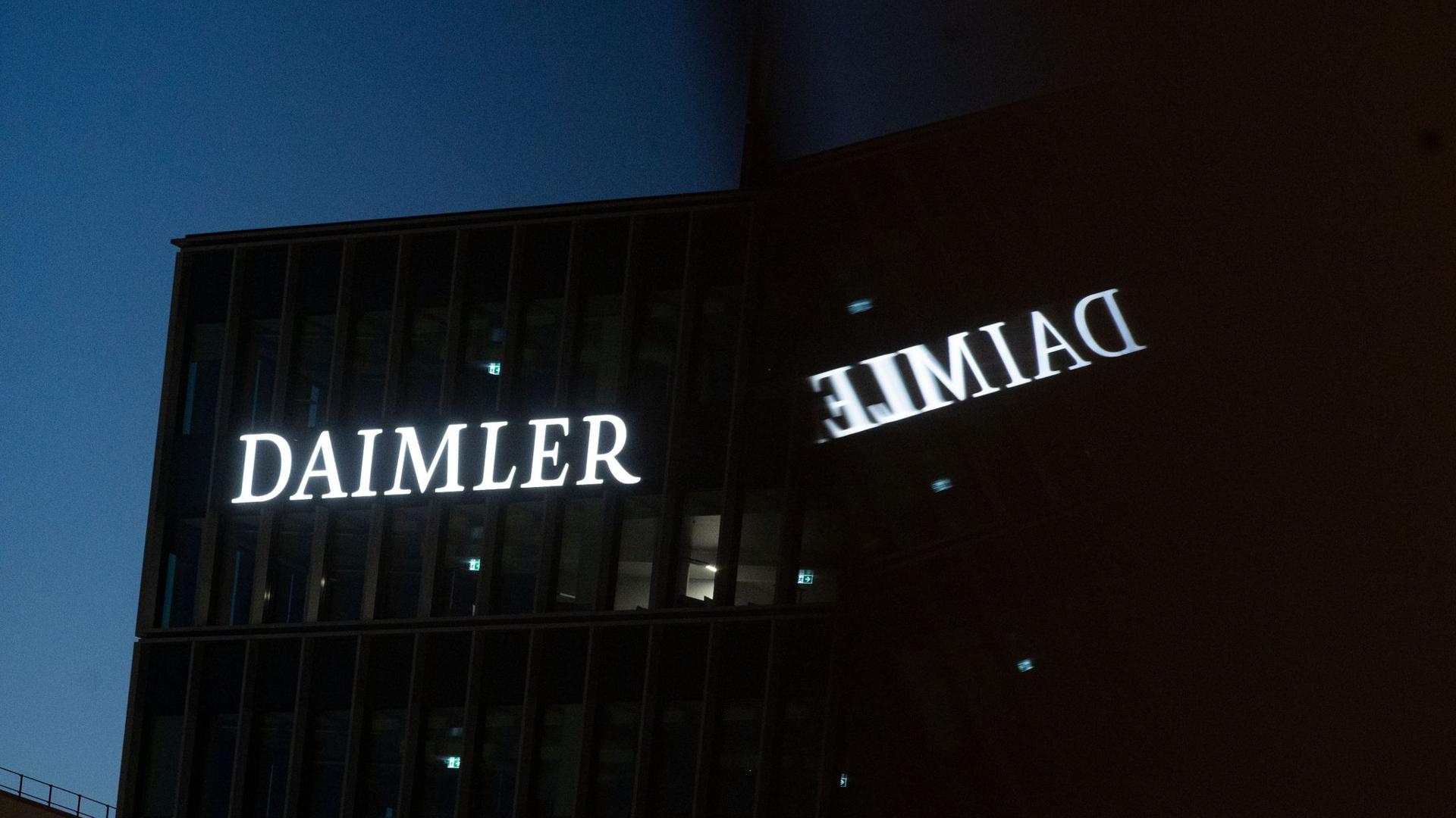 Die Zentrale des Autobauers Daimler spiegelt sich in einem Fenster.