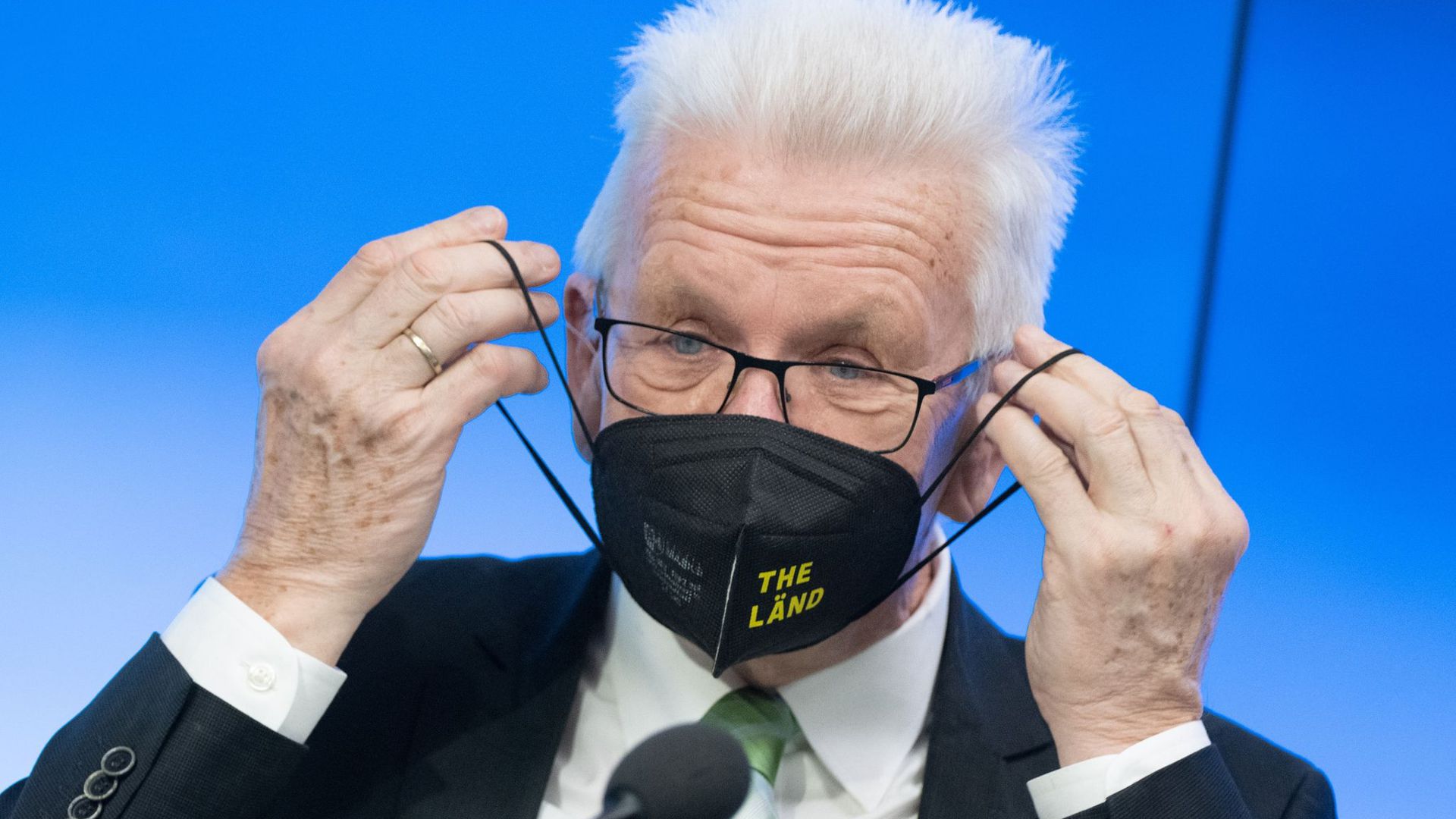 Winfried Kretschmann setzt sich nach einer Regierungs-Pressekonferenz eine Maske auf.