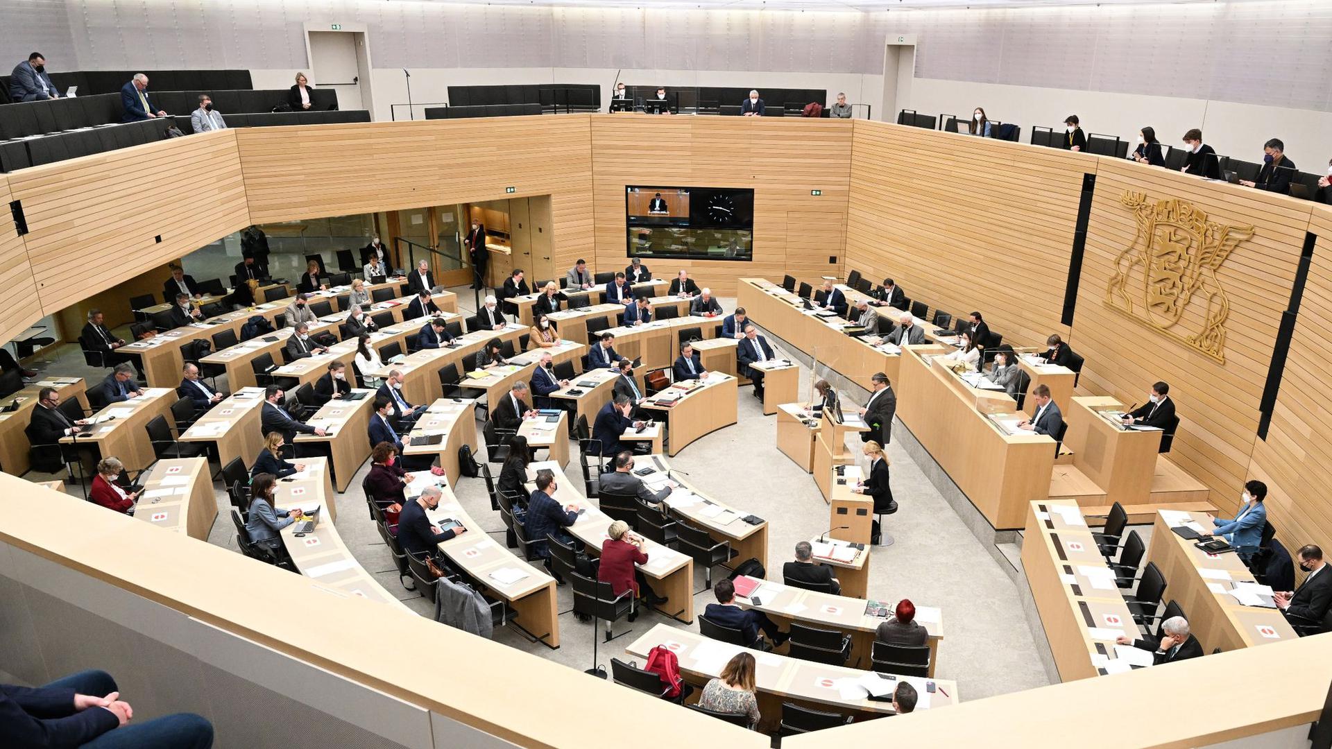Abgeordnete des Landtags von Baden-Württemberg sitzen bei einer Debatte im Plenum.
