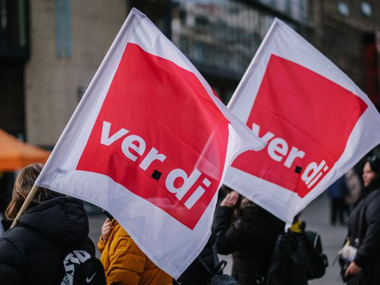 Beschäftigte nehmen mit Verdi-Fahnen an einer Demonstration teil.
