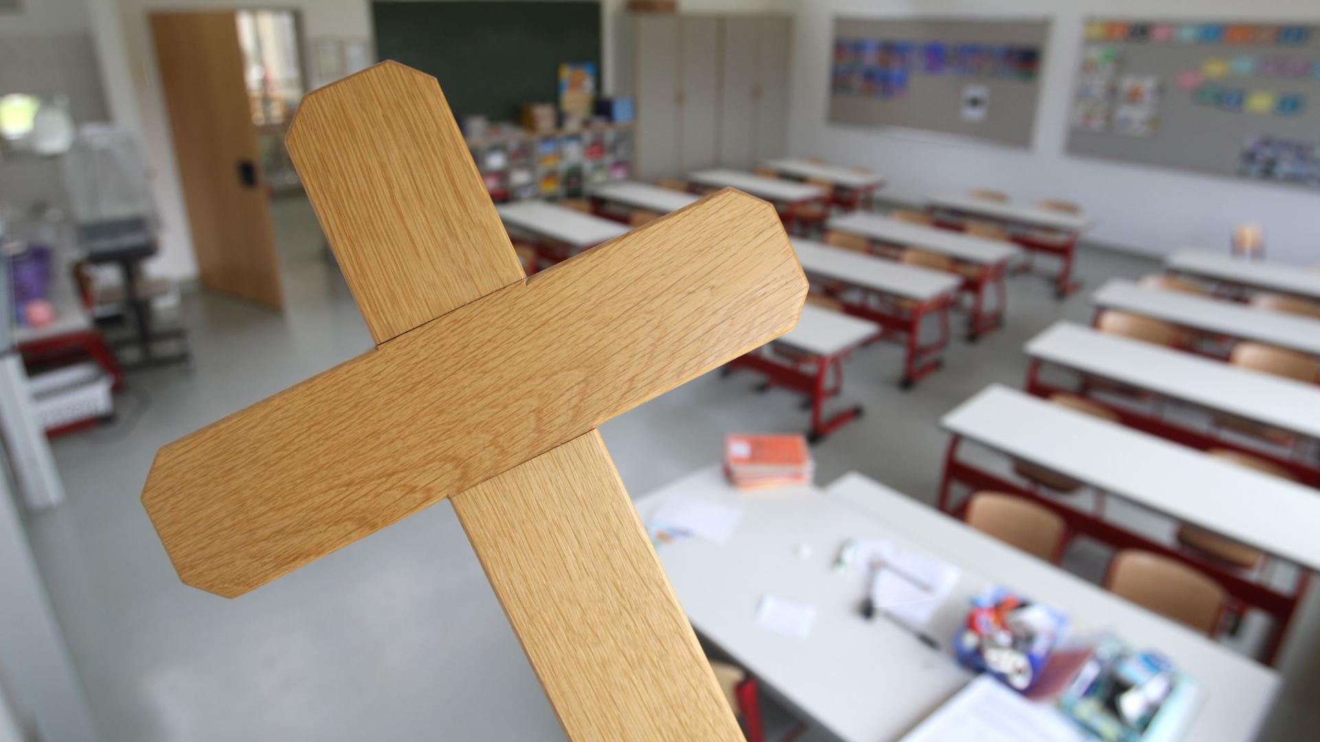 Ein Kreuz wird im Klassenzimmer einer Grundschule gehalten.