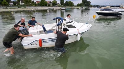 Fünf Männer vom Untersee schieben das Motorboot mit dem Namen „Nice day“ aus dem Hafen von Iznang.