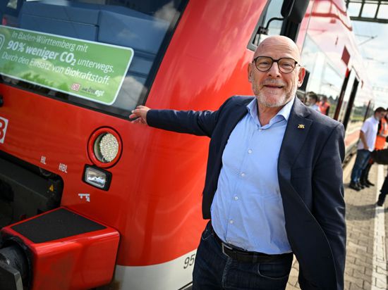 Baden-Württembergs Verkehrsminister Winfried Hermann steht neben einem Regionalzug.