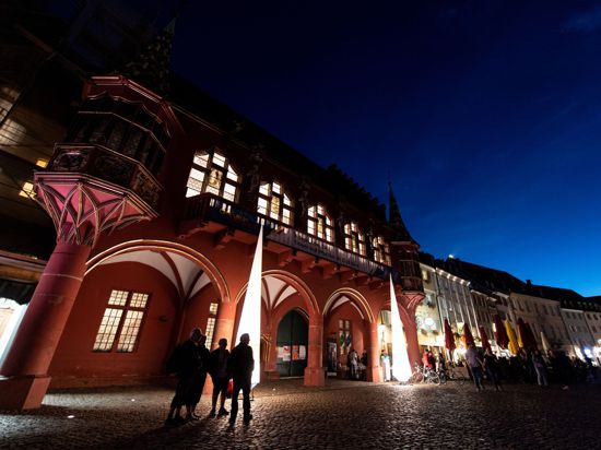 Menschen stehen während der Nacht des offenen Denkmals vor dem historischen Kaufhaus in Freiburg.