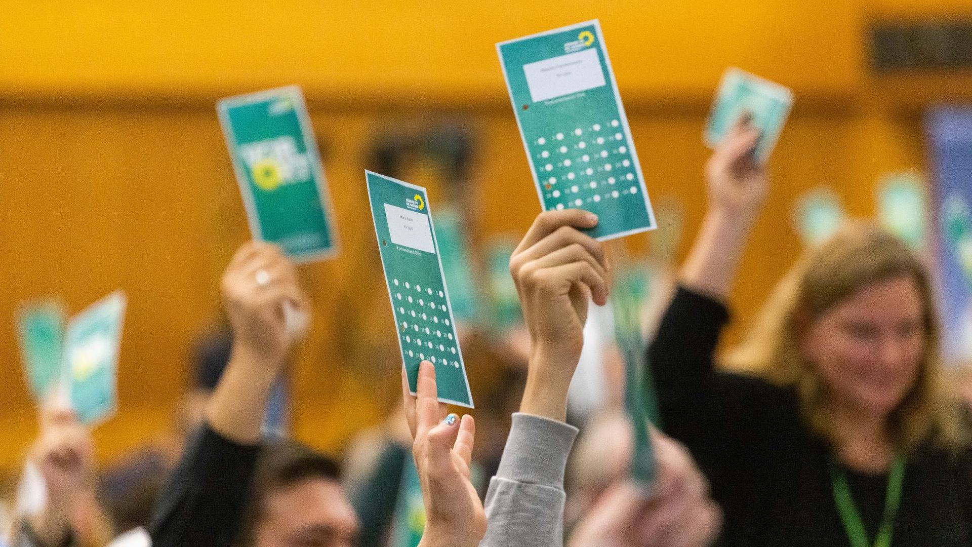 Delegierte der Grünen halten Stimmkarten in die Höhe.