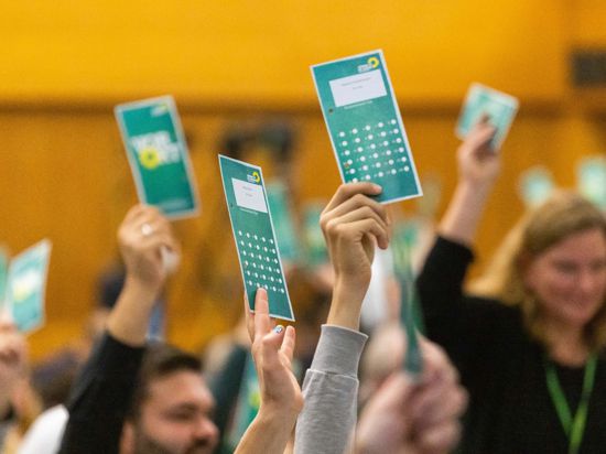 Delegierte der Grünen halten Stimmkarten in die Höhe.