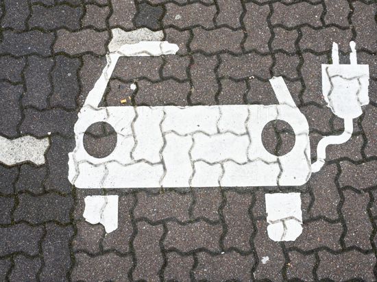 Ein Symbol für E-Autos ist auf einem Parkplatz zu sehen.