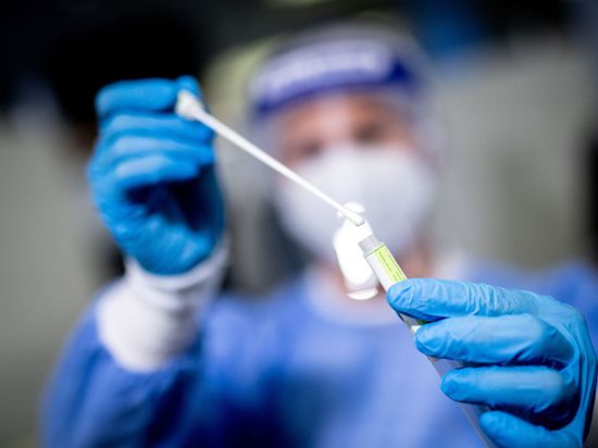 Eine medizinische Mitarbeiterin hält in einem Corona-Testzentrum ein Abstrichstäbchen in der Hand.
