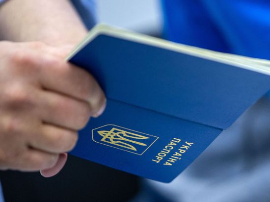 Ein Mann hält einen ukrainischen Reisepass in der Hand.