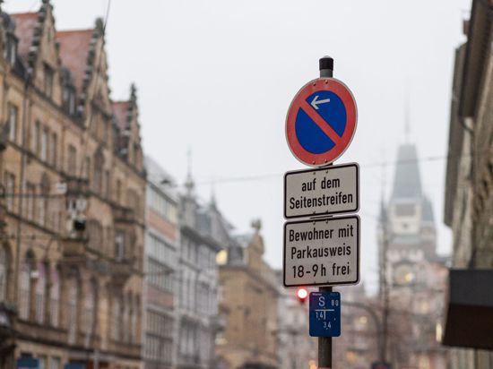 In der Innenstadt hängen Schilder mit der Aufschrift „auf dem Seitenstreifen“ und „Bewohner mit Parkausweis 18-9 h frei“.