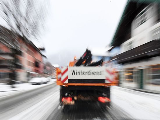 Ein Fahrzeug des Winterdienstes fährt über eine Straße.