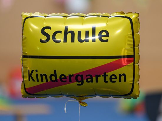 Ein Luftballon mit der Aufschrift „Schule“ und einem durchgestrichenen „Kindergarten“.