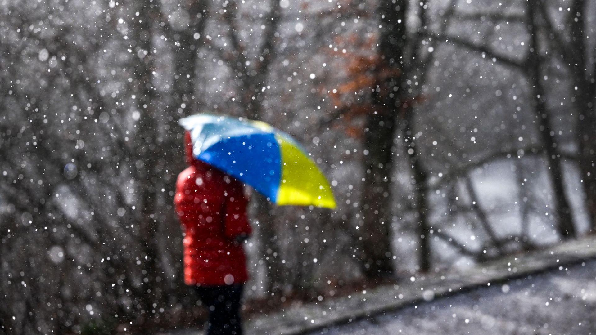 Eine Spaziergängerin geht mit einem Regenschirm bei Sonnenschein spazieren.