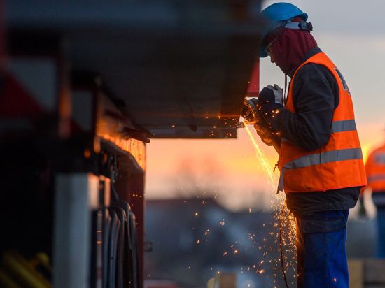 Ein Arbeiter führt auf einer Baustelle Schweißarbeiten an einer Brücke aus.