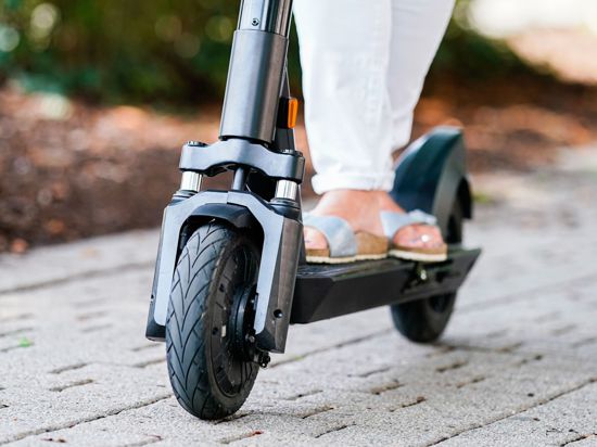 Eine Frau fährt einen E-Scooter auf einem Fuß- und Radweg.