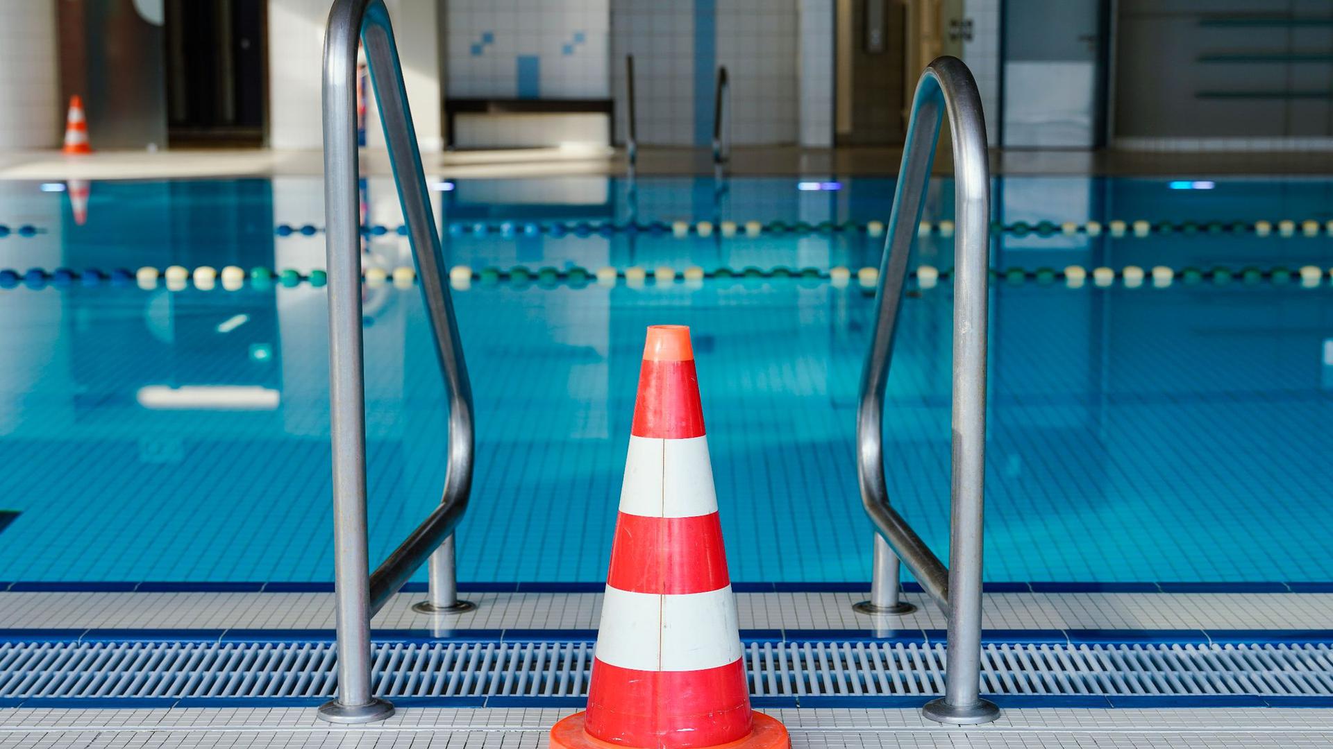 Eine Pylone steht in einem geschlossenen Hallenbad am Schwimmbecken.