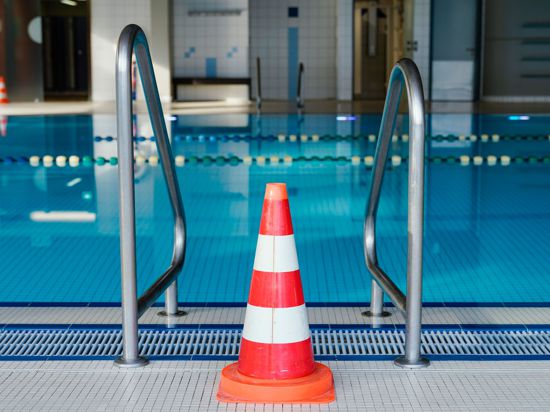 Eine Pylone steht in einem geschlossenen Hallenbad am Schwimmbecken.