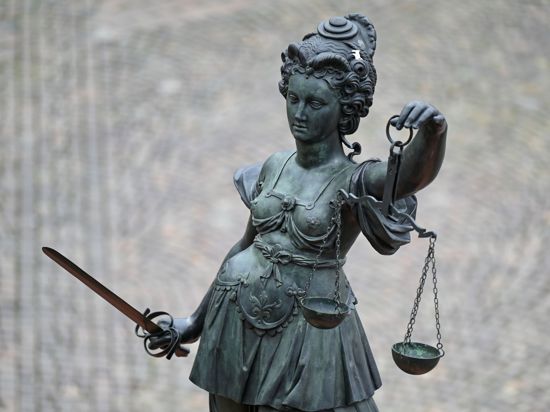 Eine Statue der Justitia hält eine Waage und ein Schwert in der Hand.