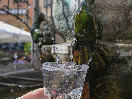 Am Hans-Im-Glück-Trinkwasserbrunnen in der Stuttgarter Innenstadt wird ein Glas mit Trinkwasser gefüllt.