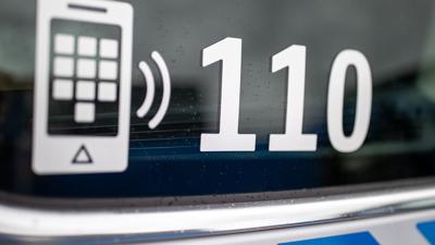 Der Nummer des Polizeinotrufs 110 steht auf der Scheibe eines Polizeifahrzeugs.