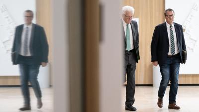 Winfried Kretschmann (Bündnis 90/Die Grünen) und Peter Hauk (CDU, r) gehen zu einer Landespressekonferenz.