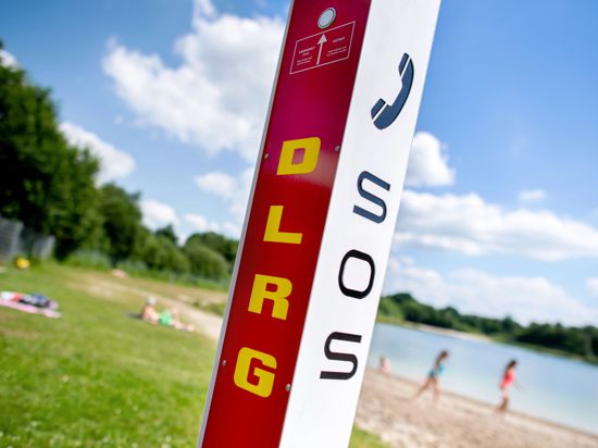 Eine Notrufsäule der DLRG steht an einem Badesee.