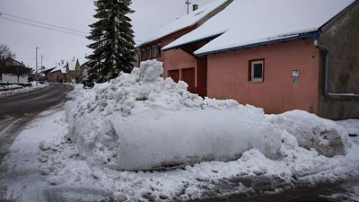 Ein von einem Räumfahrzeug aufgeschobener Schneehaufen liegt am Straßenrand.