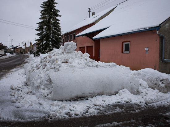 Ein von einem Räumfahrzeug aufgeschobener Schneehaufen liegt am Straßenrand.