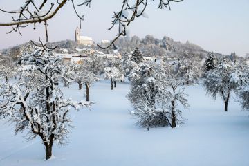 Der Berg Bussen mit seiner Wallfahrtskirche und das unterhalb gelegene Dorf Offingen in Oberschwaben sind am Morgen mit Schnee bedeckt.