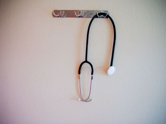 Ein Stethoskop hängt in einem Krankenhaus an einer Garderobe.
