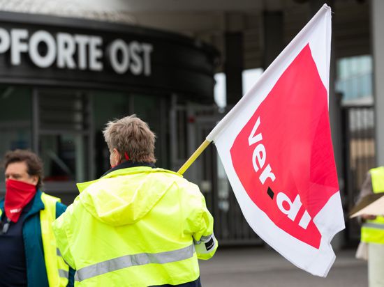 Ein Demonstrant steht mit einer Ver.di Fahne vor der Pforte Ost am Stuttgarter Flughafen.