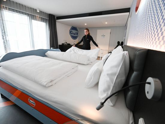 Eine Angestellte des V8 Hotels in Böblingen richtet ein Bett in einem Themenzimmer, in dem die Front eines Autos an ein Bett gestaltet ist.