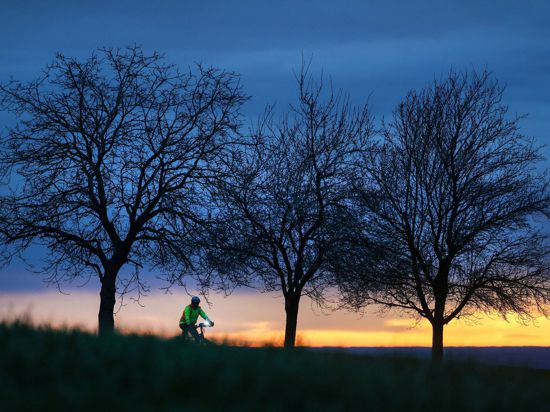 Ein Radfahrer ist am Morgen kurz nach Sonnenaufgang unterwegs.