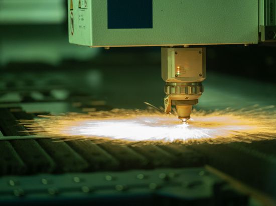 In einer Vorführ-Betriebshalle eines Maschinenbau-Unternehmens arbeitet eine Laserschneidemaschine an einem Werkstück.