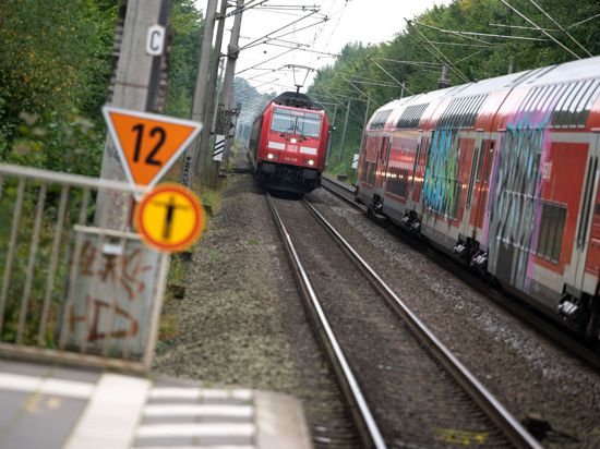 Zwei Regionalzüge der Deutschen Bahn (DB) begegnen sich vor einem Bahnhof.