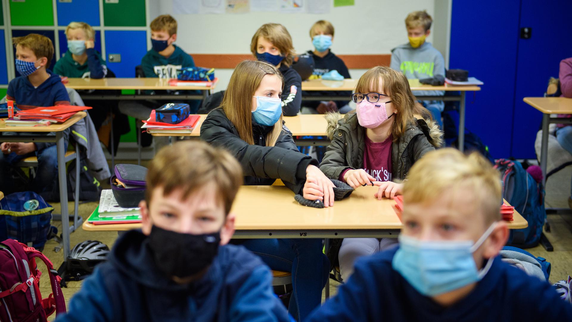 Schüler einer sechsten Klasse sitzen während des ersten Unterrichts in ihrem Klassenzimmer und tragen dabei eine Alltagsmaske.