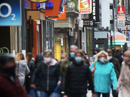 Menschen gehen mit Schutzmasken durch die Fußgängerzone. 