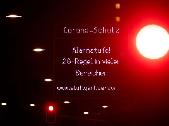 Eine Anzeige weist in der Stuttgarter Innenstadt auf die Corona-Alarmstufe «2G-Regel in vielen Bereichen!» hin, während eine Ampel ein rotes Signal zeigt. 