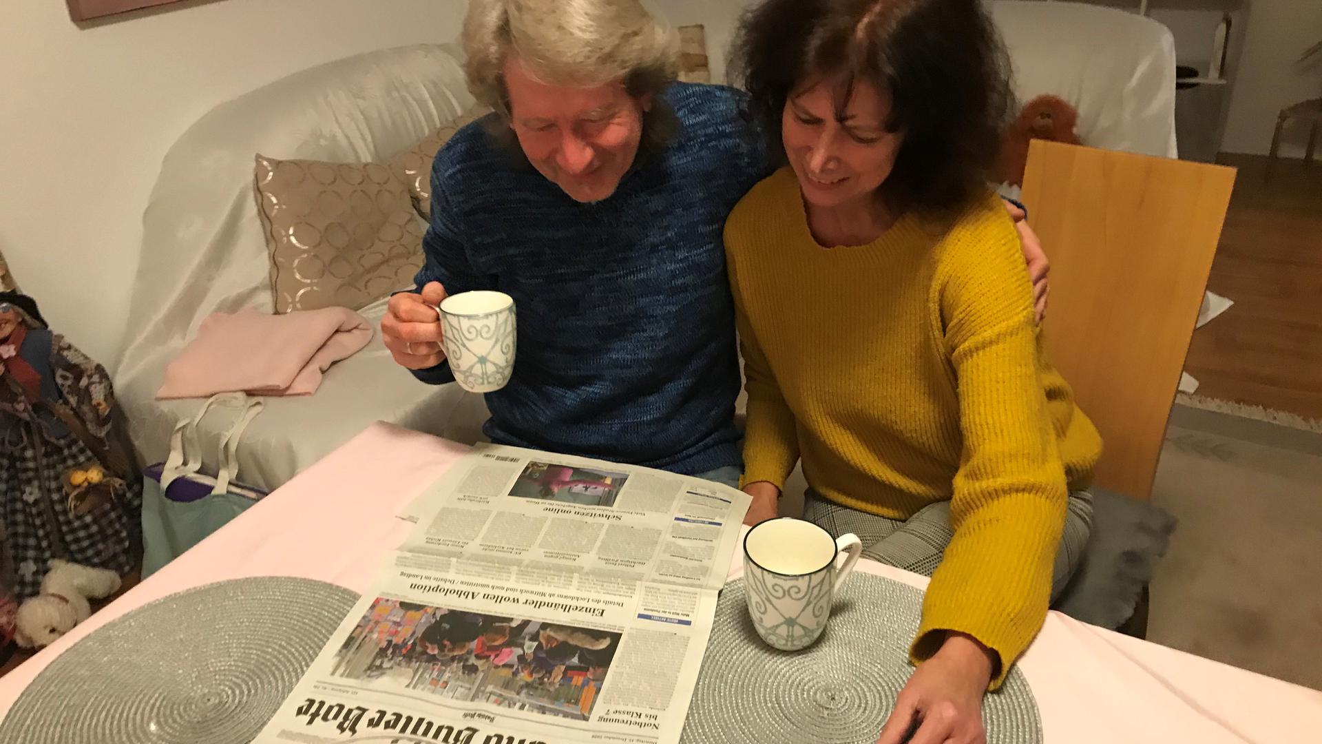 Zwei Personen lesen Zeitung am Tisch