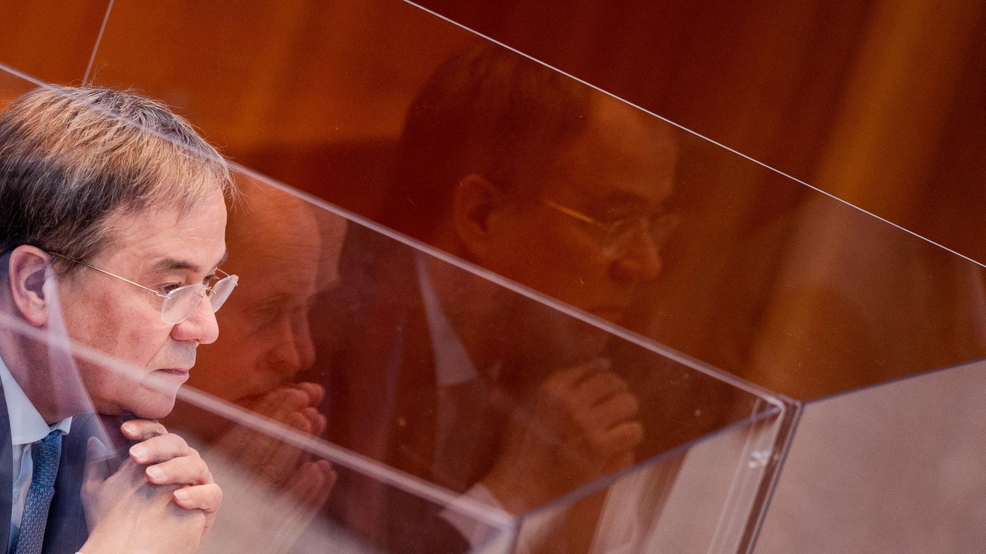 Armin Laschet sitzt in einer Box aus Plexiglas im Plenum des Landtags.