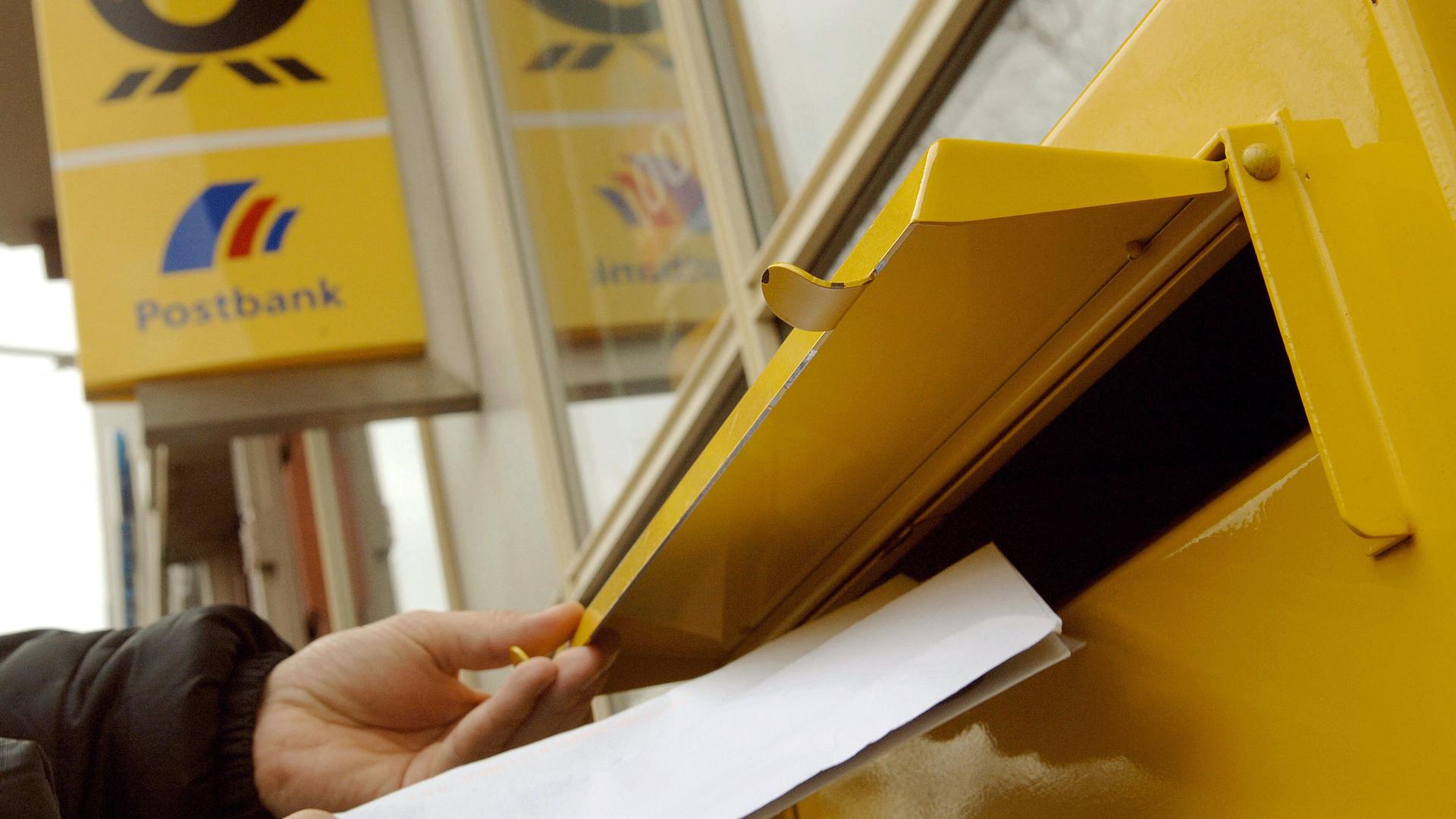 Briefe werden in einen Briefkasten vor einer Filiale der Deutschen Post eingeworfen.