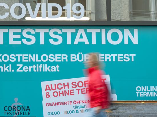 25.08.2021, Bayern, München: Eine Person geht im Stadtteil Schwabing an einer Covid-19 Teststation vorbei, die auch kostenlose Bürgertest inklusiv Zertifikat und ohne Termin anbietet. Foto: Peter Kneffel/dpa +++ dpa-Bildfunk +++