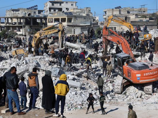 Rettungskräfte und Anwohner durchsuchen die Trümmer eingestürzter Gebäude nach Überlebenden.