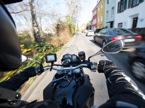 Ein Motorradfahrer fährt durch eine Wohngegend.