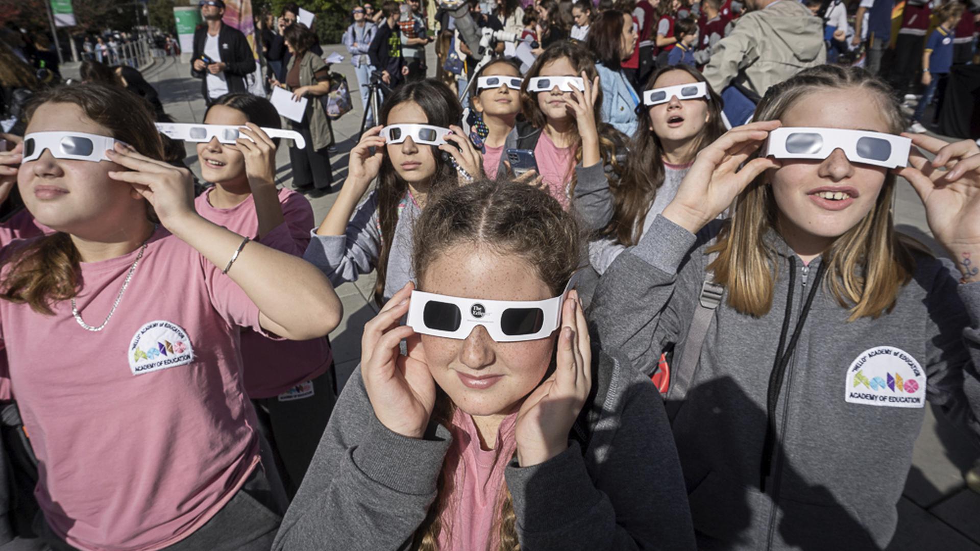 Kosovo, Pristina: Jugendliche mit Sonnenbrillen beobachten eine partielle Sonnenfinsternis.