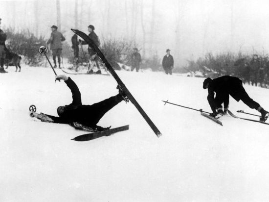 Skifahrer stürzen bei trübem Wetter einen Hang hinunter.